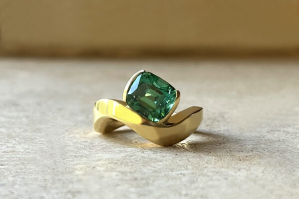 Cushion cut green tourmaline set in half bezel setting, chunky curved 18k yellow gold band